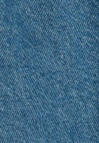 Tela de mezclilla de color azul medio, con un clásico tejido de sarga que presenta una textura sutil y sin patrones ni acentos visibles.