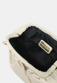 Borsa a mano in similpelle crema con design arricciato, ferramenta dorata e fodera interna nera. Presenta un'etichetta interna con il nome del marchio.