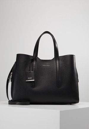 Czarna torebka typu tote z fakturowanej skóry z podwójnymi uchwytami, odpinanym paskiem na ramię oraz metalową metką z logo na środku przedniej części.