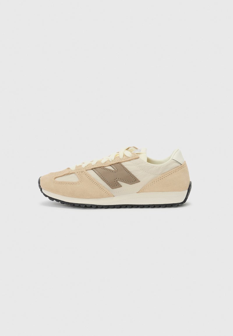 Beige retrostiilis tossud, mis on valmistatud siidist, kreemja välistalla ja tumeda kummitalda. Omab silmapaistvat heleda pruunikate logo küljes.