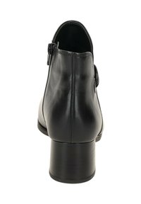Zwarte leren enkelboot met blokhak, zijrits en decoratieve zijgesp, van achteren weergegeven op een witte achtergrond.