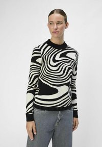 Maglione in nero e crema con motivo a strisce ondulate, collo rotondo, polsini e orlo a costine. Texture intrecciata, design aderente.