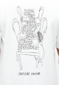 Dibujo lineal de una mesa de comedor dispuesta con platos, tenedores y sillas, con texto manuscrito sobre volver a casa para la temporada festiva.