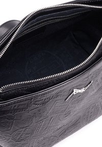 Wnętrze czarnej skórzanej torebki z wytłaczanymi wzorami, podbite czarnym materiałem, z zamknięciem na srebrny zamek błyskawiczny i kieszonką.