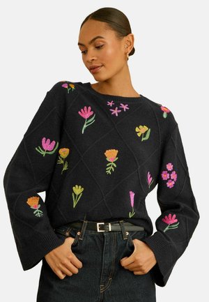 Schwarzer Pullover mit mehrfarbiger Blumenstickerei, die ein Rautenmuster zeigt, lange Ärmel und Rundhalsausschnitt. Fein gestrickte Textur.