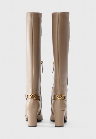 Knee-high beige leather boots with a square heel, gold logo accents, and side zippers. Smooth texture and fitted design.