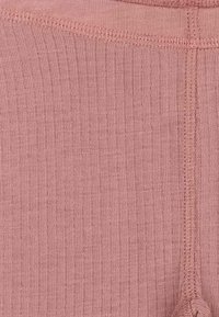 Rosa pink ribbet stof med fin struktur. Har synlige sømme og en sidesøm. Materialet ser blødt og let ud.