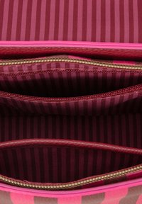 Interieur van een roze gestreepte handtas met twee ritscompartimenten, voorzien van een rijke bordeauxrode voering met verticale strepen. Textuur materiaal.