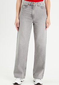 Jeans de talle alto y pierna ancha en denim gris claro con un acabado desgastado. Cuenta con cinco bolsillos y cierre de botón.