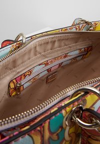 Multikleurige handtas interieur met een gemusterd doek, met een ritsvak en verschillende compartimenten; gevoerd met beige stof.