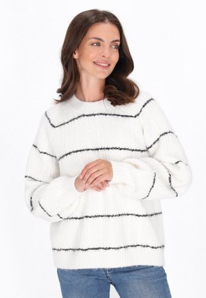 Witte fluffy trui met zwarte horizontale strepen, ribbeltextuur, ronde halslijn en een ontspannen pasvorm, gecombineerd met blauwe jeans.