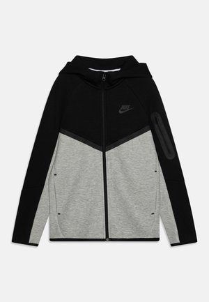 Nike Zip-Hoodie in Schwarz und Grau mit Chevron-Design, Logo auf der Brust, seitlicher Reißverschlusstasche und elastischen Bündchen. Weicher Stoff.