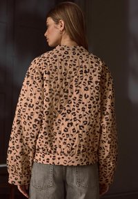 Quilted jakke i blush pink med sort leopardprint, med ribbet kant og brede ærmer, lavet af blødt, struktureret stof.