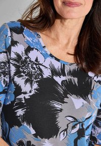 Langärmliges Oberteil mit floralem Muster in Schwarz, Blau und Hellgrau. Weicher Stoff mit rundem Halsausschnitt und detaillierten floralen Akzenten.
