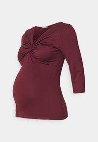 Maternity top in burgundy, featuring a gathered front design, three-quarter sleeves, and a smooth, stretchy fabric for comfort.