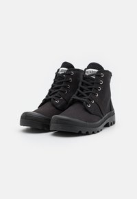 Botas de tobillo negras de lona con puntera redonda, diseño con cordones, ojales de metal y suela de goma con un patrón de tacos para mayor tracción.