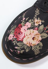 Czarne buty z materiału z kwiatowym wzorem w odcieniach różowym, kremowym i zielonym; charakteryzują się teksturowaną powierzchnią oraz gumową podeszwą z różowym ściegiem.