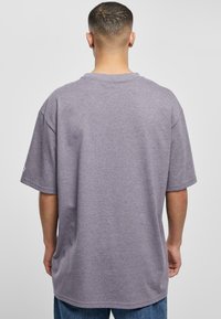 Gray oversized cotton T-shirt with short sleeves, crew neckline, and a smooth texture. Features a tag on the left sleeve.