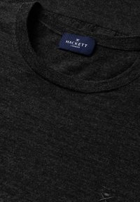 Černé tričko s kulatým výstřihem vyrobené z texturované látky, s modrou nášivkou "HACKETT LONDON". Design má jednoduchý, klasický vzhled.