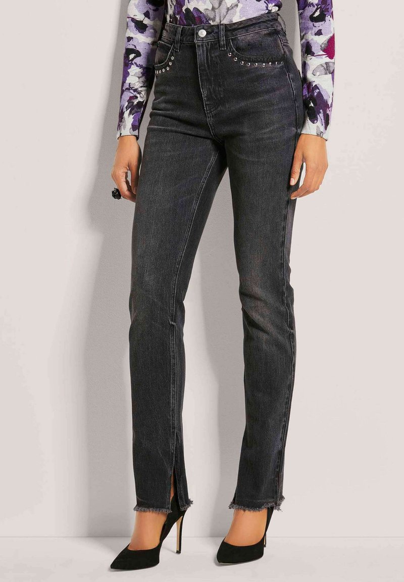 Zwarte denim jeans met een hoge taille, voorzakken versierd met zilveren studs en zijsplitten aan de onderkant. Gefrustreerde details aan de onderzijde.