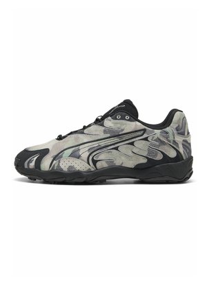 Niedriger Sportschuh mit schwarzer Sohle, schwarz-grauem Camouflage-Muster und wellenförmigen Design-Overlays an der Seite.