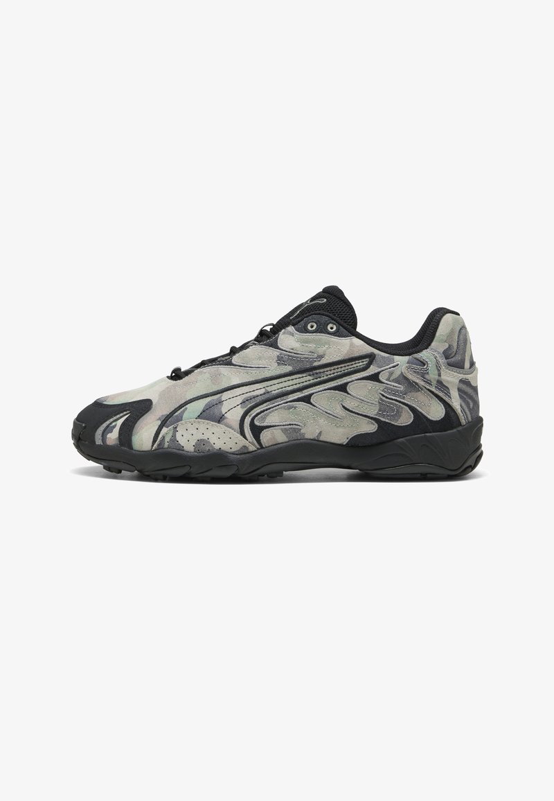 Chaussure de sport basse avec semelle noire, motif camouflage noir et gris, et superpositions de design ondulées sur le côté.