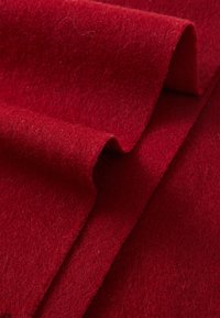 Tissu en feutre rouge avec une texture douce, présentant des plis doux et superposés, ainsi qu'une couleur profonde et uniforme.