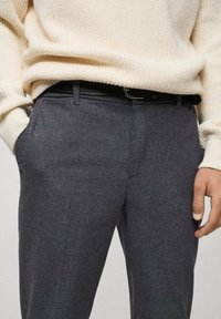 Pantaloni gri din lână cu un front plat, buzunare laterale și o curea neagră. Materialul are o textură moale, oferind un aspect smart-casual.