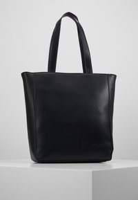 Sac à tote en cuir noir avec un design structuré, des côtés plats et deux longues poignées, présentant une texture lisse et un matériel minimal.