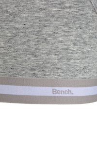 Sivi bombažni material z gladko teksturo, ki vključuje svetlo sivo elastično pasnico okrašeno z blagovno znamko "Bench." in belo črto.