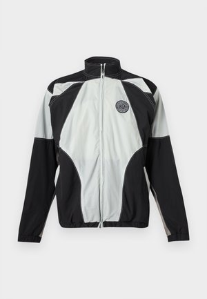 Juoda ir pilka sportinė striukė su užtrauktuku, aukštu apykakliu ir apvaliu logotipo lopu ant kairės krūtinės, pateikta ant balto fono.