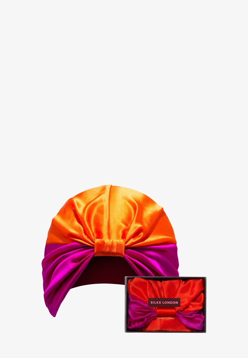 Jedwabny turban w kolorze pomarańczowym i różowym z zawiązanym przodem. W zestawie znajduje się pasująca jedwabna pudełko do przechowywania. Teksturowane satynowe wykończenie.