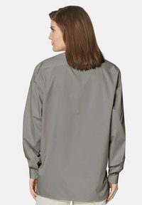 Grijze lange mouw shirt met een knoopsluiting-kraag, met een zachte textuur en een relaxte pasvorm. De achterkant toont schoudernaden en manchetdetails.