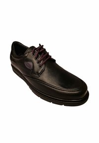 Zapato de cuero negro con una textura suave, punta redondeada y cordones oscuros. Presenta costuras detalladas y una suela acolchada para mayor comodidad.