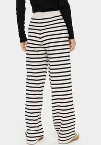 Bredbeniga byxor i mjukt tyg med horisontella svartvita ränder, med elastisk midja och avslappnad passform.