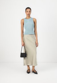 Lyseblå ribbet strikket tanktop kombinert med et langt beige skjørt, svart håndveske og svarte leppestifter med sløyfeakkenter.
