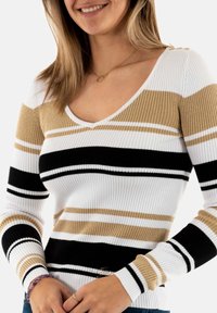 Maglione a coste con righe orizzontali in bianco, nero e tonalità di beige. Design con scollatura a V e dettagli con bottoni sulle spalle.