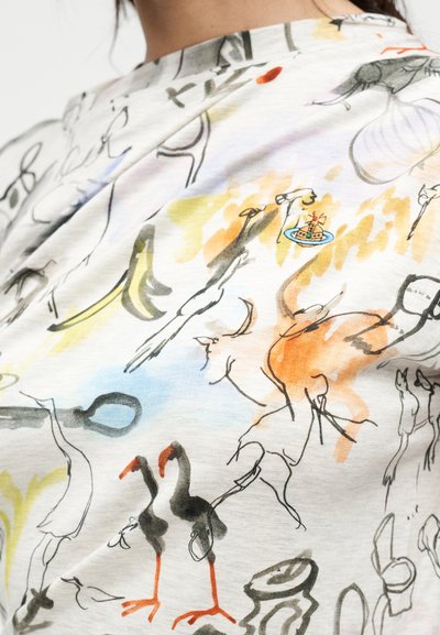 Βαμβακερό μπλουζάκι με πολύχρωμο αφηρημένο σχέδιο που περιλαμβάνει διάφορα ζωγραφισμένα σχήματα και φιγούρες, μεταξύ των οποίων δύο μαύρα πουλιά με κόκκινα πόδια.