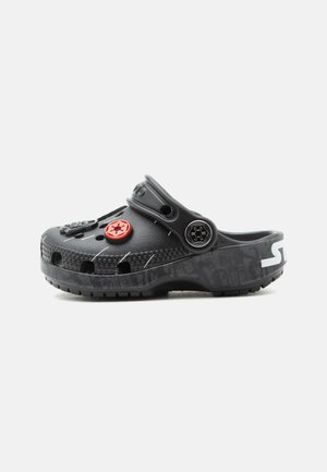 Μαύρο τσόγκι με οπές αερισμού, ρυθμιζόμενο λουράκι και κόκκινα και μαύρα διακοσμητικά κουμπιά σε σχήμα αστεριού στην κορυφή και στο πλάι.