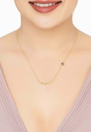 Gold necklace with a wavy, decorative pendant featuring small stones and a round purple accent, suspended from a delicate chain.