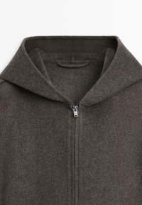 Brun uld-zip-hoodie med en stor, foldet krave og en glat lynlås. Stoffet virker blødt og let tekstureret med få syninger.