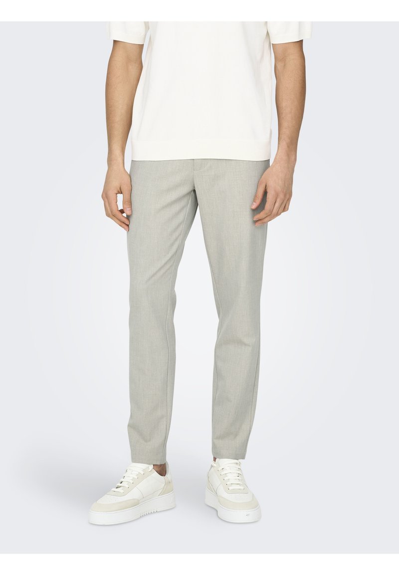Pantalones de corte recto en gris claro confeccionados en un tejido suave, con un ajuste slim y un patrón minimalista, combinados con zapatillas blancas.