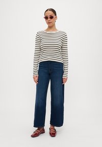 Stripet langsarmet skjorte i beige og sort, høy midje bred-bein blå jeans og blanke burgunder sko med stropp detaljer.