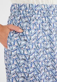Pantalons à motifs avec une taille élastique. Présente des formes géométriques en bleu, bleu clair et rose pâle. Comprend des poches latérales.