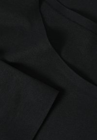 Tissu en coton noir avec une texture douce, présentant un design simple, une surface lisse et un léger éclat, plié pour exposition.