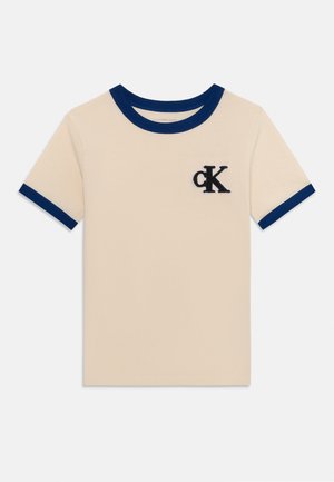T-shirt beige à manches courtes avec col et poignets de manches bleu marine, arborant un logo brodé noir "cK" sur la poitrine.