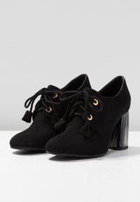 Svarta mocka ankelskor med rundad tå, guldögon, svarta rep-snören, fransar och en spegelblandad klack.