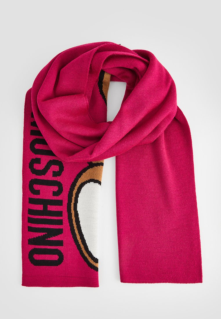 Rosa gestrickter Schal mit einem auffälligen grafischen Design, auf dem der Text "Moschino" sowie ein illustriertes Charakterdetail abgebildet sind. Weiche Textur.