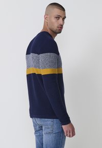 Marineblauer Pullover mit horizontale Streifen in hellgrau und senfgelb. Rippstruktur, Rundhalsausschnitt, lange Ärmel, schlanke Passform.