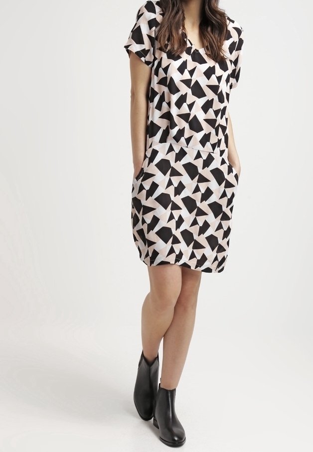 Korta ärmar klänning i ett geometriskt svartvitt mönster på en ljusrosa bakgrund, med avslappnad passform och sidfickor.